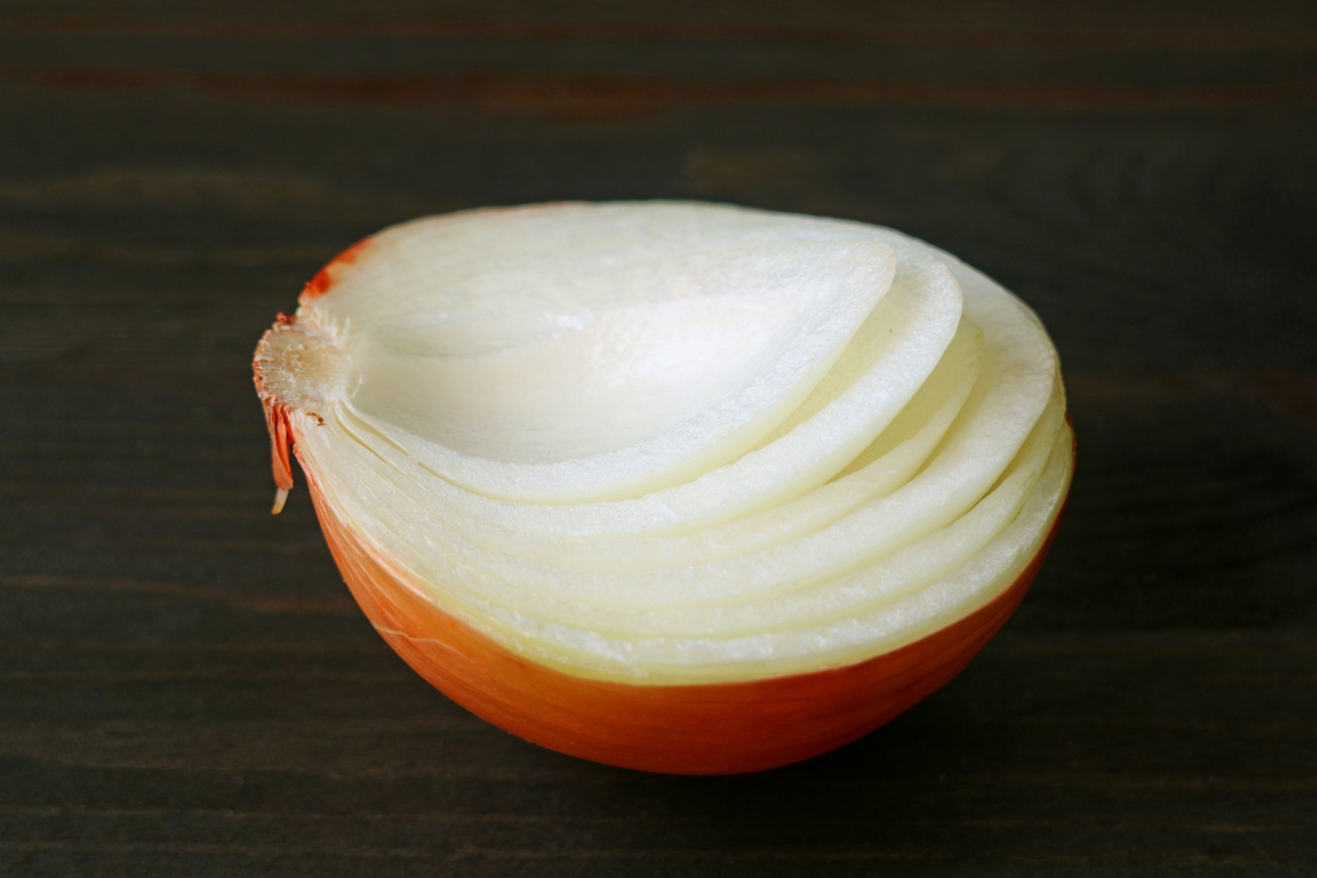 Closed up a cut in half onion which showing its inside layers isolated on dark color background